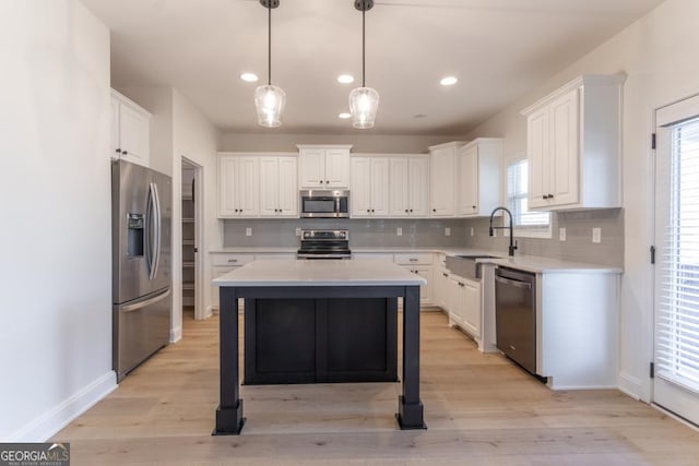 kitchen with appliances with stainless steel finishes, white cabinets, light countertops, and a sink