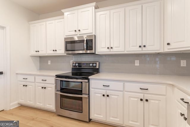 kitchen featuring light wood-type flooring, appliances with stainless steel finishes, white cabinets, and light countertops