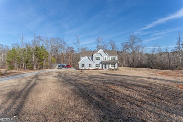 view of front of property with a forest view, a porch, and a front lawn