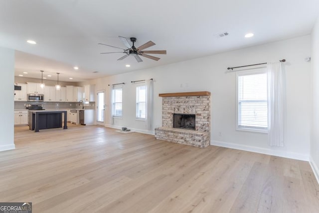 unfurnished living room with light wood finished floors, a brick fireplace, visible vents, and recessed lighting