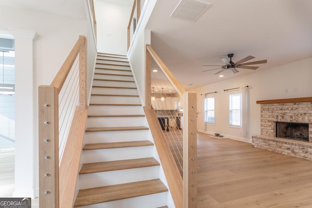 stairway featuring visible vents, ceiling fan, wood finished floors, a stone fireplace, and recessed lighting