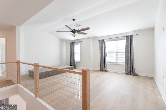 unfurnished room with a wealth of natural light, vaulted ceiling, baseboards, and wood finished floors