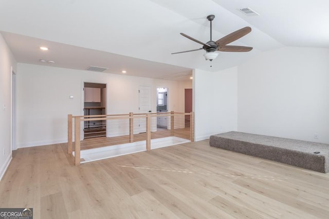 spare room with lofted ceiling, light wood finished floors, and visible vents