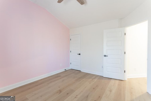 unfurnished bedroom featuring lofted ceiling, light wood-type flooring, a ceiling fan, and baseboards