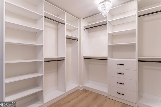 spacious closet with an inviting chandelier and light wood-style flooring