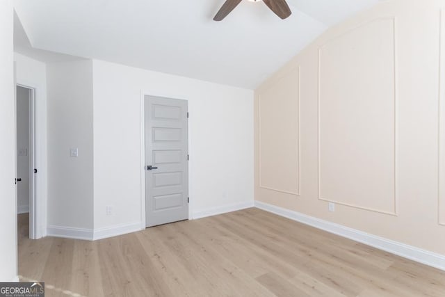 empty room featuring baseboards, ceiling fan, vaulted ceiling, and light wood-style floors