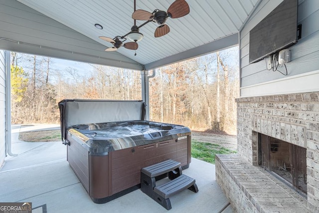 view of patio featuring a hot tub, an outdoor brick fireplace, and ceiling fan