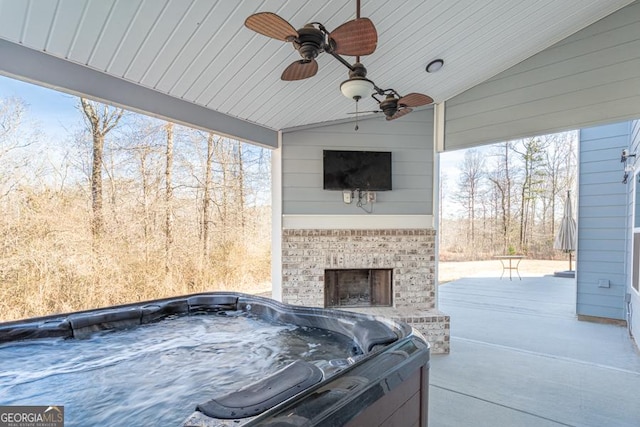 view of patio / terrace with a hot tub, an outdoor brick fireplace, and a ceiling fan