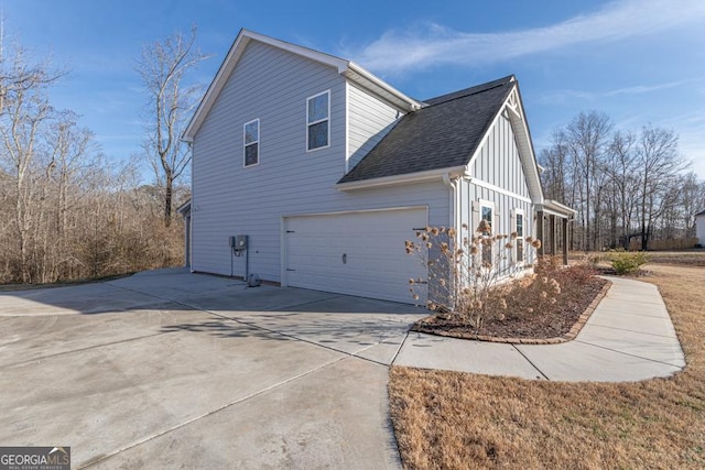 view of side of home featuring a garage, roof with shingles, board and batten siding, and concrete driveway