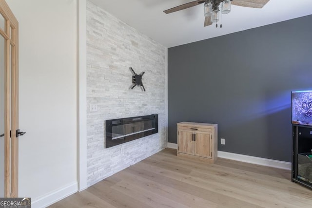 living area featuring a fireplace, wood finished floors, a ceiling fan, and baseboards