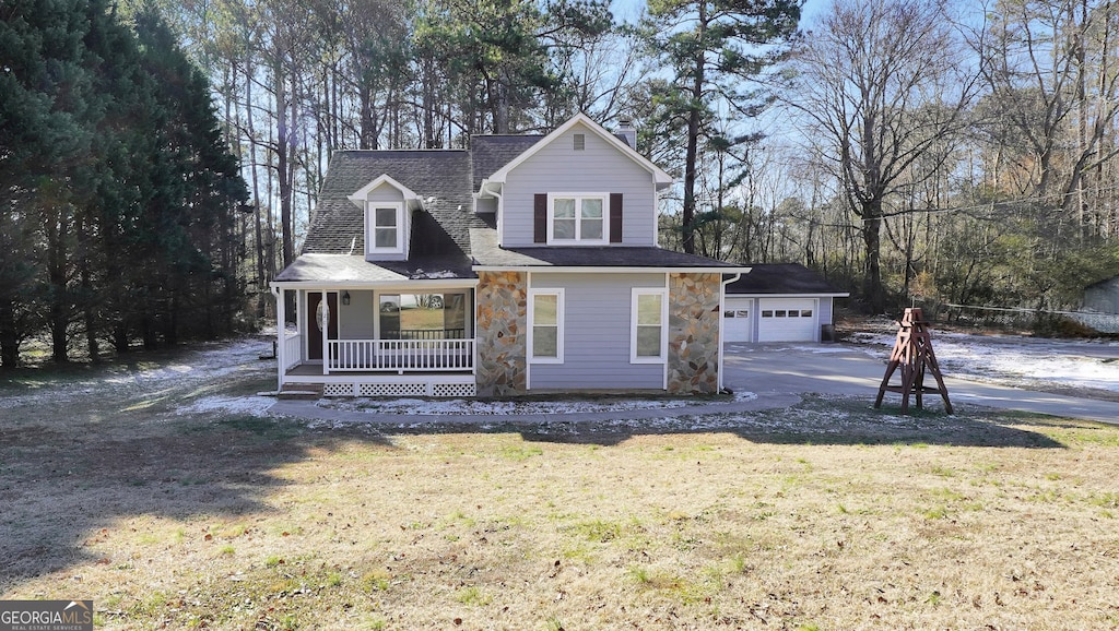 view of front of property featuring an outbuilding, a garage, a front yard, and a porch