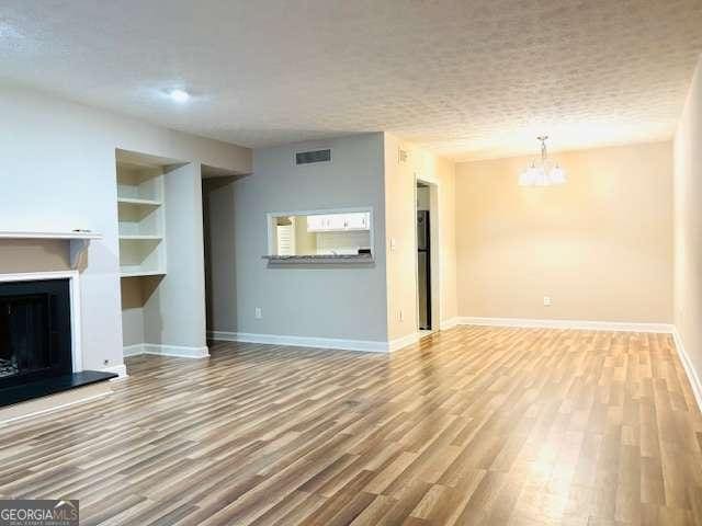 unfurnished living room featuring hardwood / wood-style flooring, a notable chandelier, and built in features