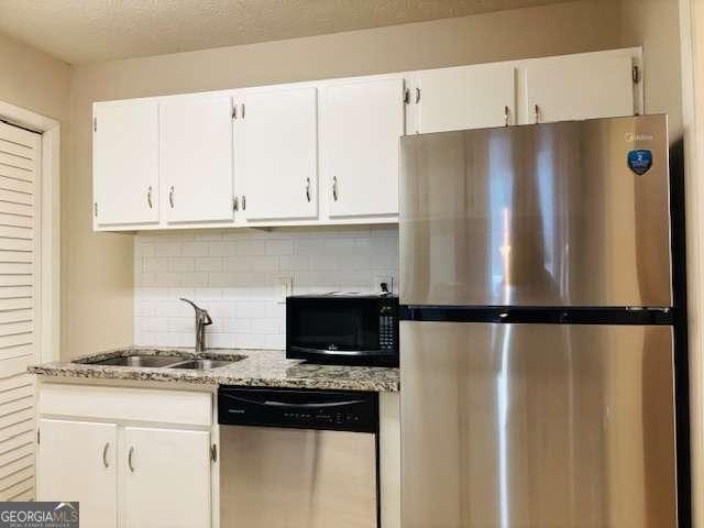 kitchen featuring white cabinetry, sink, backsplash, light stone counters, and stainless steel appliances