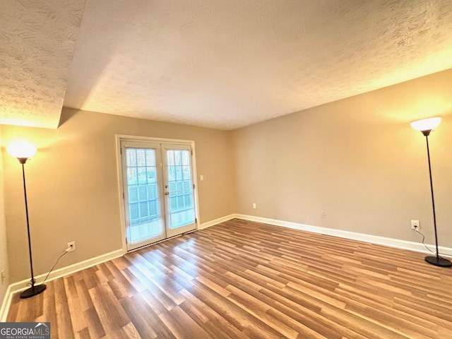 spare room featuring french doors, hardwood / wood-style floors, and a textured ceiling