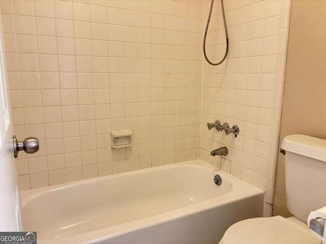 bathroom featuring toilet and tiled shower / bath