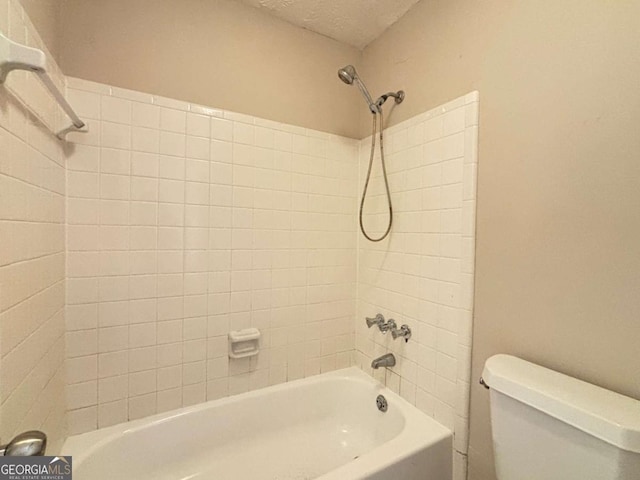 bathroom with tiled shower / bath, toilet, and a textured ceiling