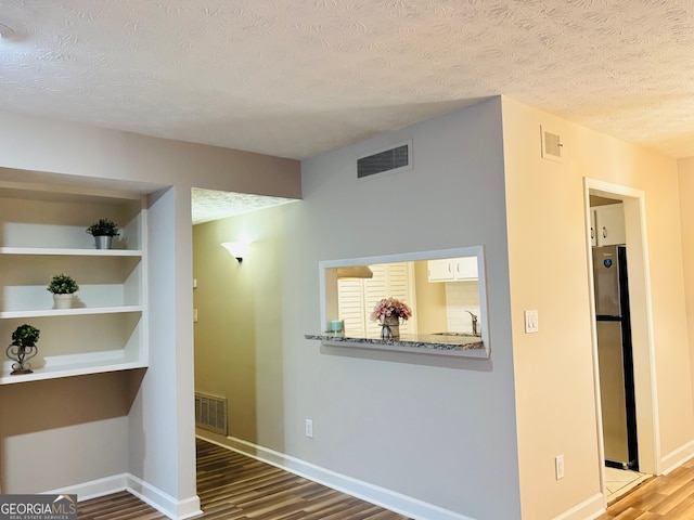 hallway with built in shelves, wood-type flooring, sink, and a textured ceiling