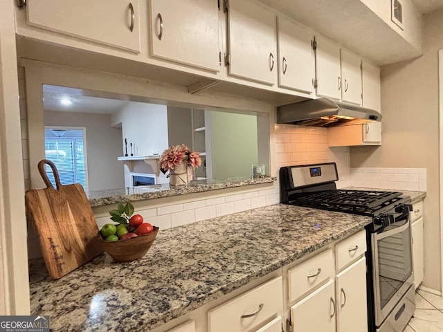 kitchen with light stone counters, backsplash, gas stove, and white cabinets