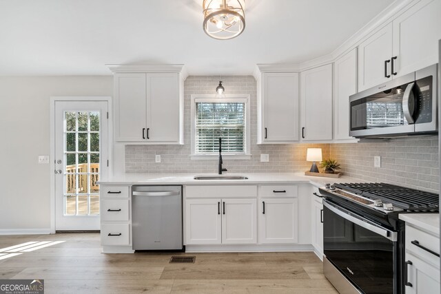 kitchen featuring stainless steel appliances, plenty of natural light, sink, and white cabinets