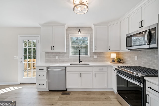 kitchen featuring a healthy amount of sunlight, appliances with stainless steel finishes, sink, and white cabinets