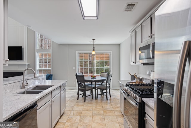 kitchen featuring sink, decorative light fixtures, gray cabinets, stainless steel appliances, and light stone countertops