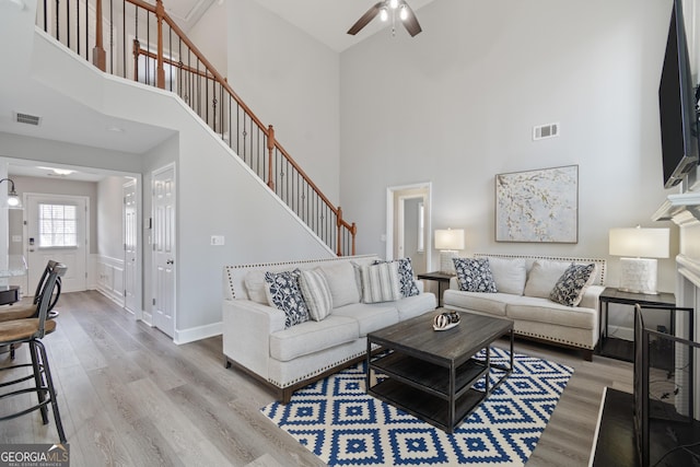 living room featuring a high ceiling, wood-type flooring, and ceiling fan