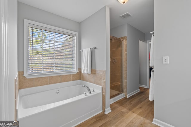 bathroom with hardwood / wood-style flooring and separate shower and tub