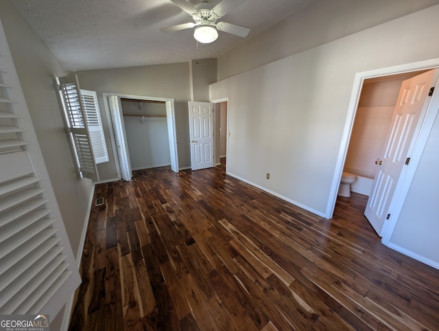 unfurnished bedroom featuring lofted ceiling, ensuite bathroom, a textured ceiling, dark hardwood / wood-style floors, and ceiling fan