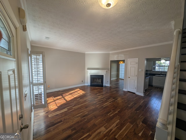 unfurnished living room with crown molding, dark hardwood / wood-style floors, sink, and a textured ceiling