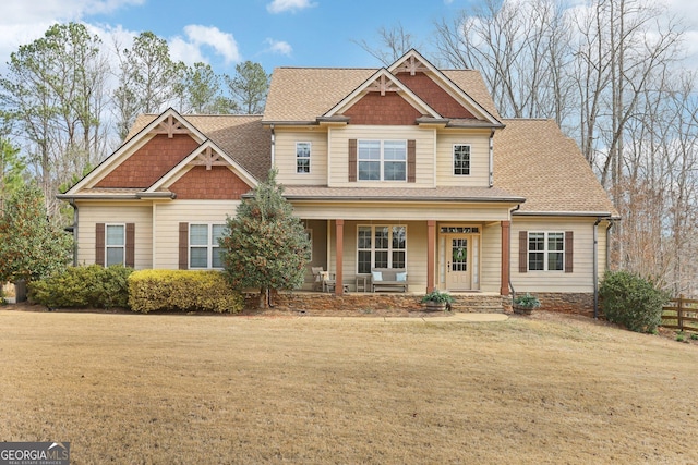 craftsman inspired home featuring a front yard, covered porch, and roof with shingles