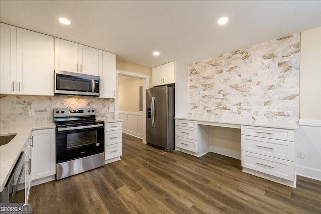 kitchen featuring dark wood-type flooring, tasteful backsplash, built in desk, stainless steel appliances, and white cabinets