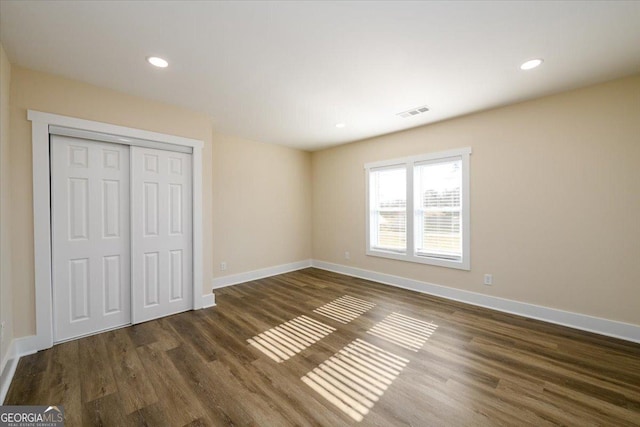 unfurnished bedroom featuring dark wood-type flooring and a closet