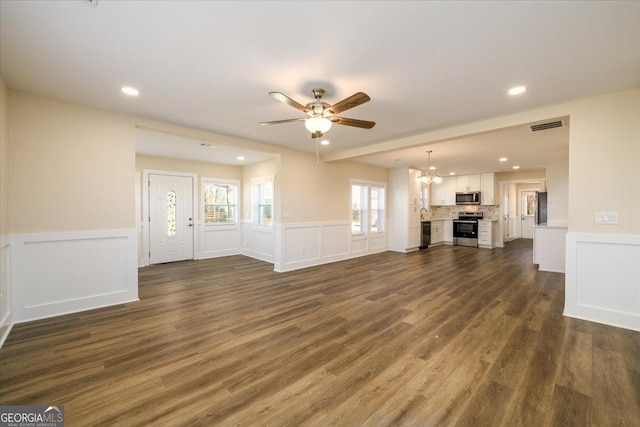 unfurnished living room featuring ceiling fan with notable chandelier and dark hardwood / wood-style flooring