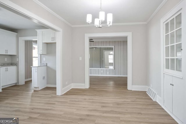 unfurnished dining area with ornamental molding, a chandelier, and light wood-type flooring