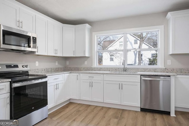 kitchen featuring white cabinetry, appliances with stainless steel finishes, sink, and light hardwood / wood-style flooring