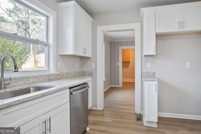 kitchen with sink, stainless steel dishwasher, light stone countertops, light hardwood / wood-style floors, and white cabinets