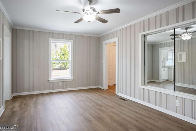 empty room with crown molding and light hardwood / wood-style flooring