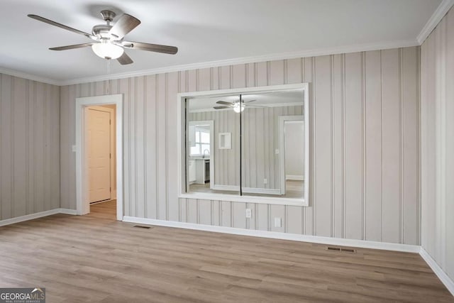 unfurnished room featuring crown molding, ceiling fan, and light wood-type flooring