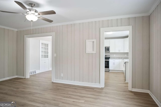 empty room with ceiling fan, ornamental molding, and light hardwood / wood-style floors