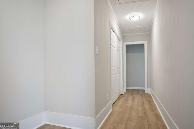 hallway featuring crown molding, light hardwood / wood-style floors, and a textured ceiling