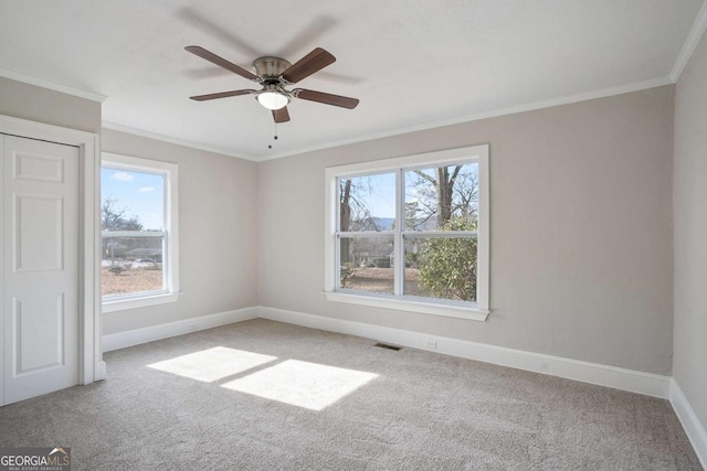 empty room featuring light carpet, ceiling fan, ornamental molding, and a healthy amount of sunlight