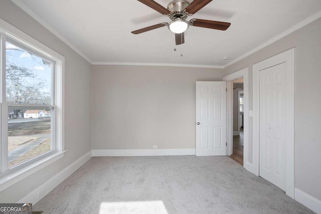 carpeted spare room with plenty of natural light, ornamental molding, and ceiling fan