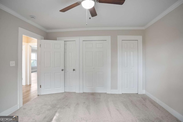 unfurnished bedroom with multiple closets, crown molding, light colored carpet, and ceiling fan