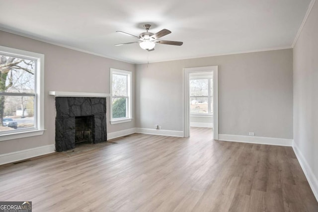 unfurnished living room with crown molding, ceiling fan, a fireplace, and light hardwood / wood-style floors