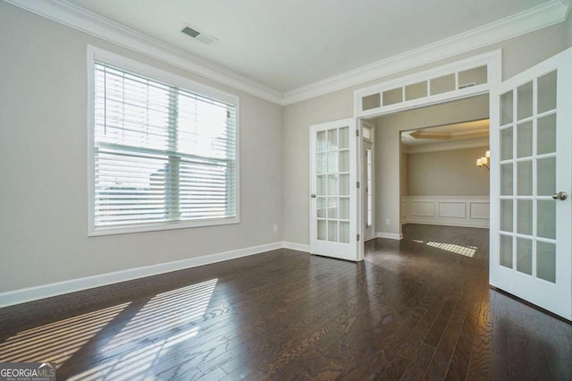 spare room featuring crown molding, dark wood-type flooring, an inviting chandelier, and french doors