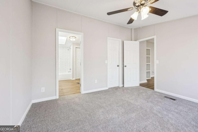 unfurnished bedroom featuring dark colored carpet, connected bathroom, and ceiling fan