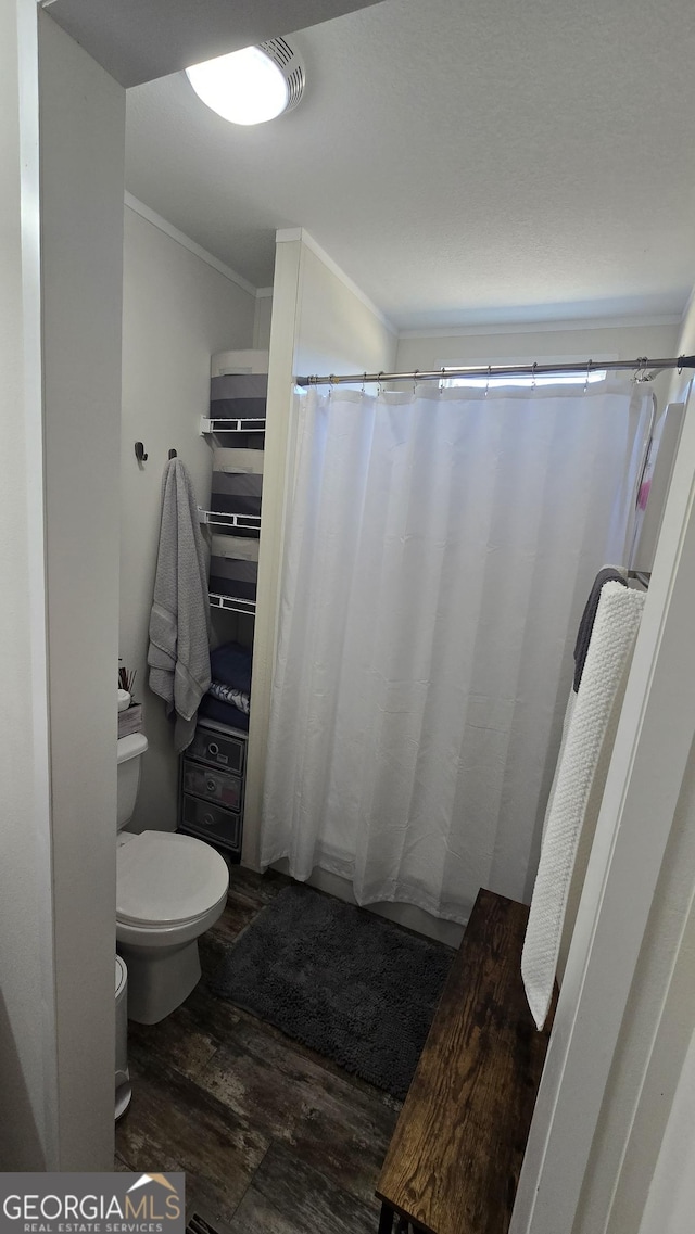 full bath featuring a shower with shower curtain, crown molding, toilet, and wood finished floors