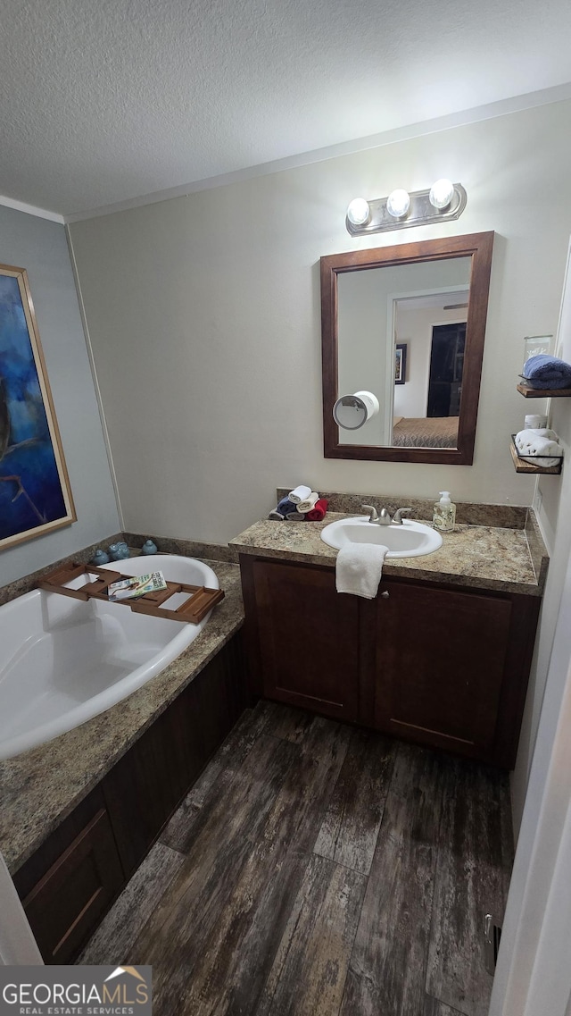 bathroom with ornamental molding, a textured ceiling, vanity, and wood finished floors