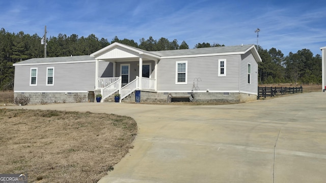 manufactured / mobile home featuring concrete driveway, a porch, and crawl space