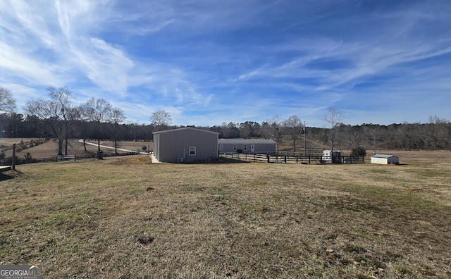 view of yard with an outbuilding, a rural view, and fence